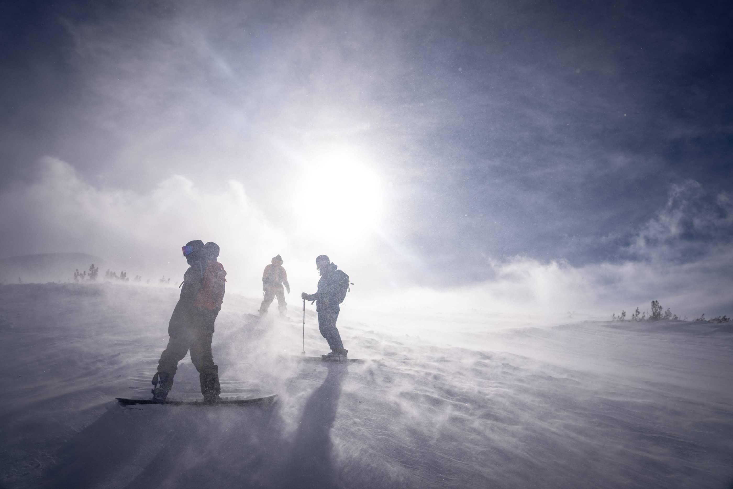 three people pause to take in the scene on a sunny backcountry skiing day