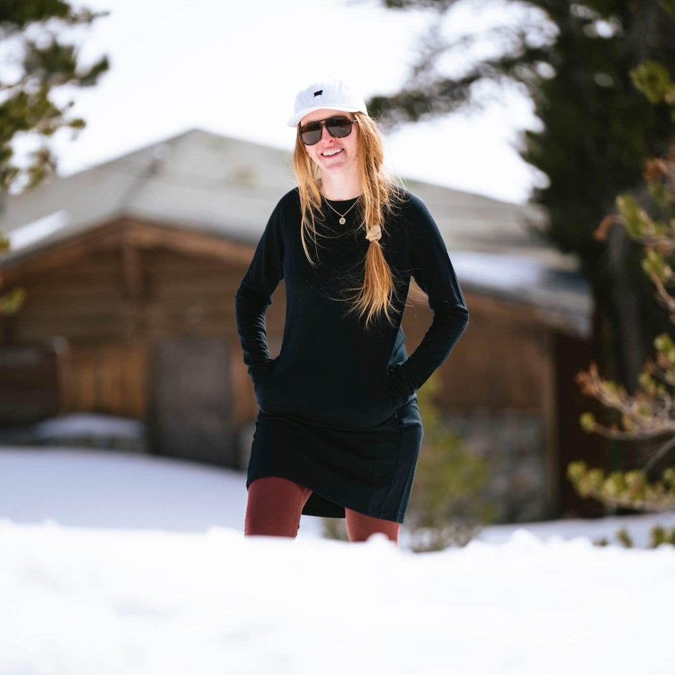 a woman walking in a black Hyde 100% Merino Dress with a white hat and red leggings