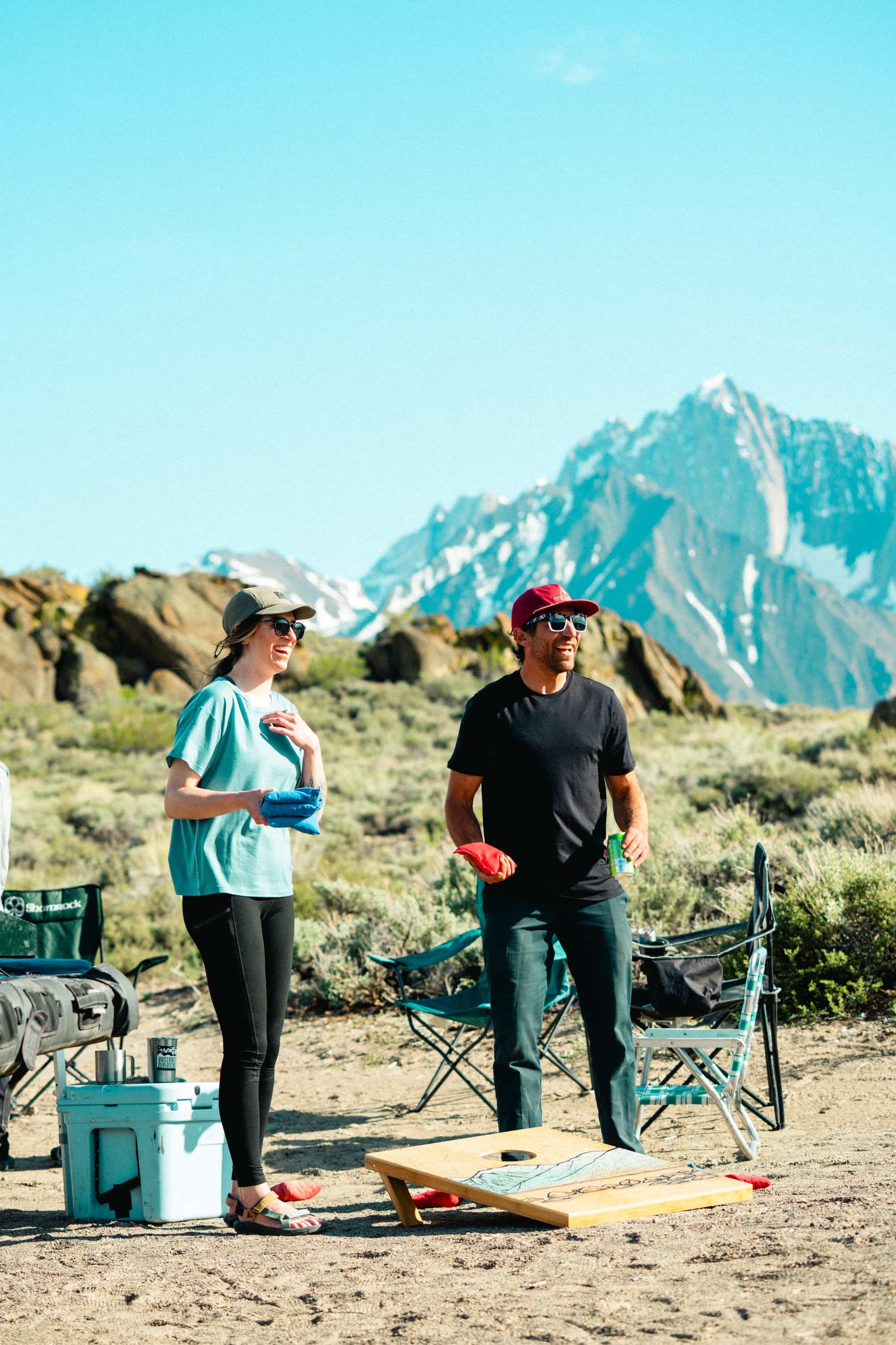 a man and a woman playing cornhole camping