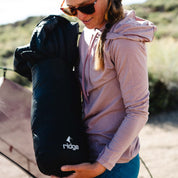a woman wearing a Solstice Sun Hoodie in Woodrose setting up camp