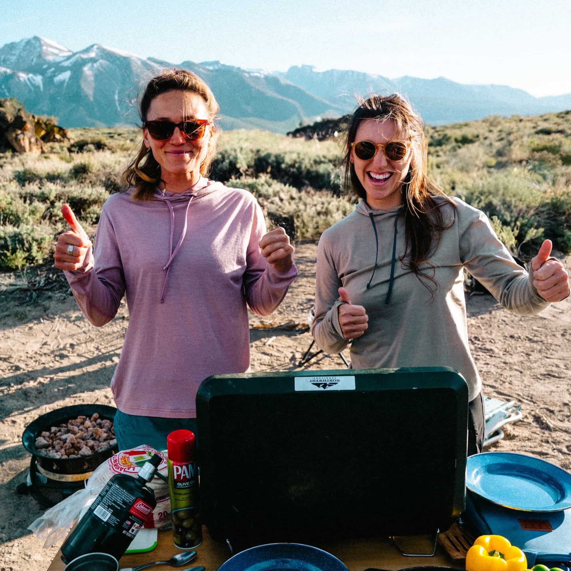 two women cooking dinner at camp wearing Solstice Sun Hoodies