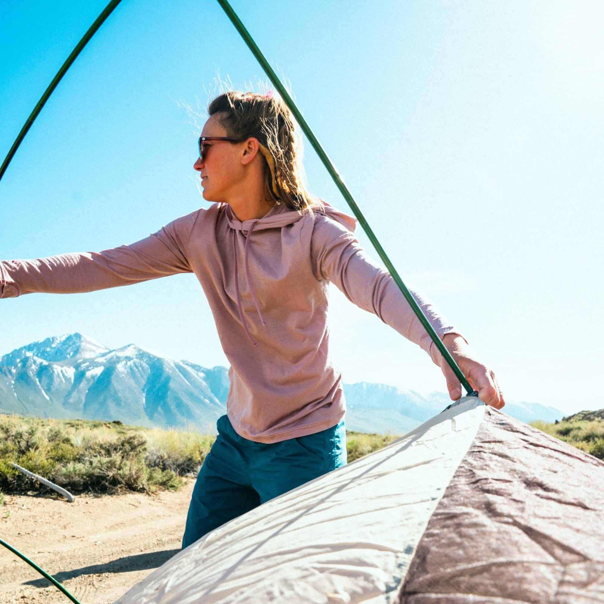 a woman setting up a tent wearing a Woodrose Solstice Sun Hoodie