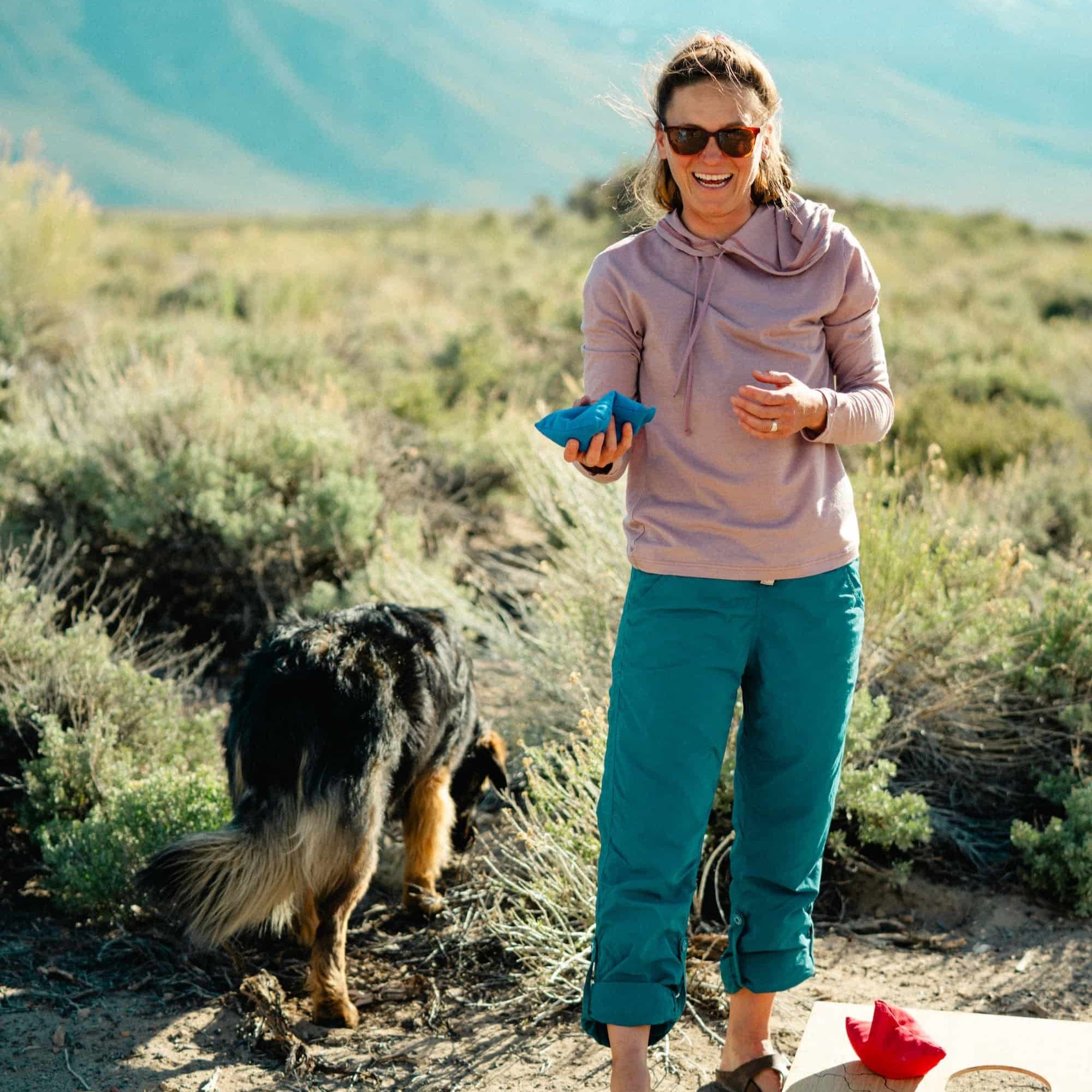 a woman playing cornhole wearing a Solstice Sun Hoodie in Woodrose