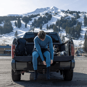 a man getting ready for a ski day on his truck tailgate in Inversion Base Layers