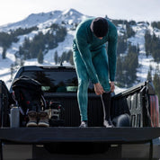 a man putting on tie-dye base layer bottoms at his truck