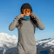 a woman layering up for a ski day wearing Ridge Inversion Base Layers and a blue neck gaiter and black beanie