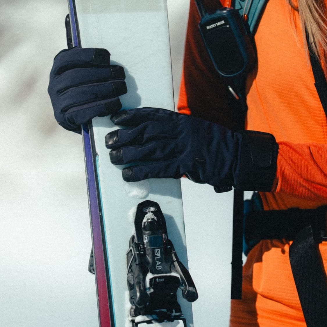a woman wearing Tioga Tour Gloves holding a pair of backcountry skis