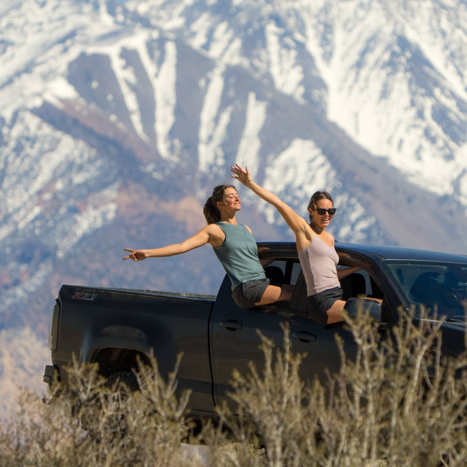 two girls hanging out of a truck wearing Ridge Merino tank tops