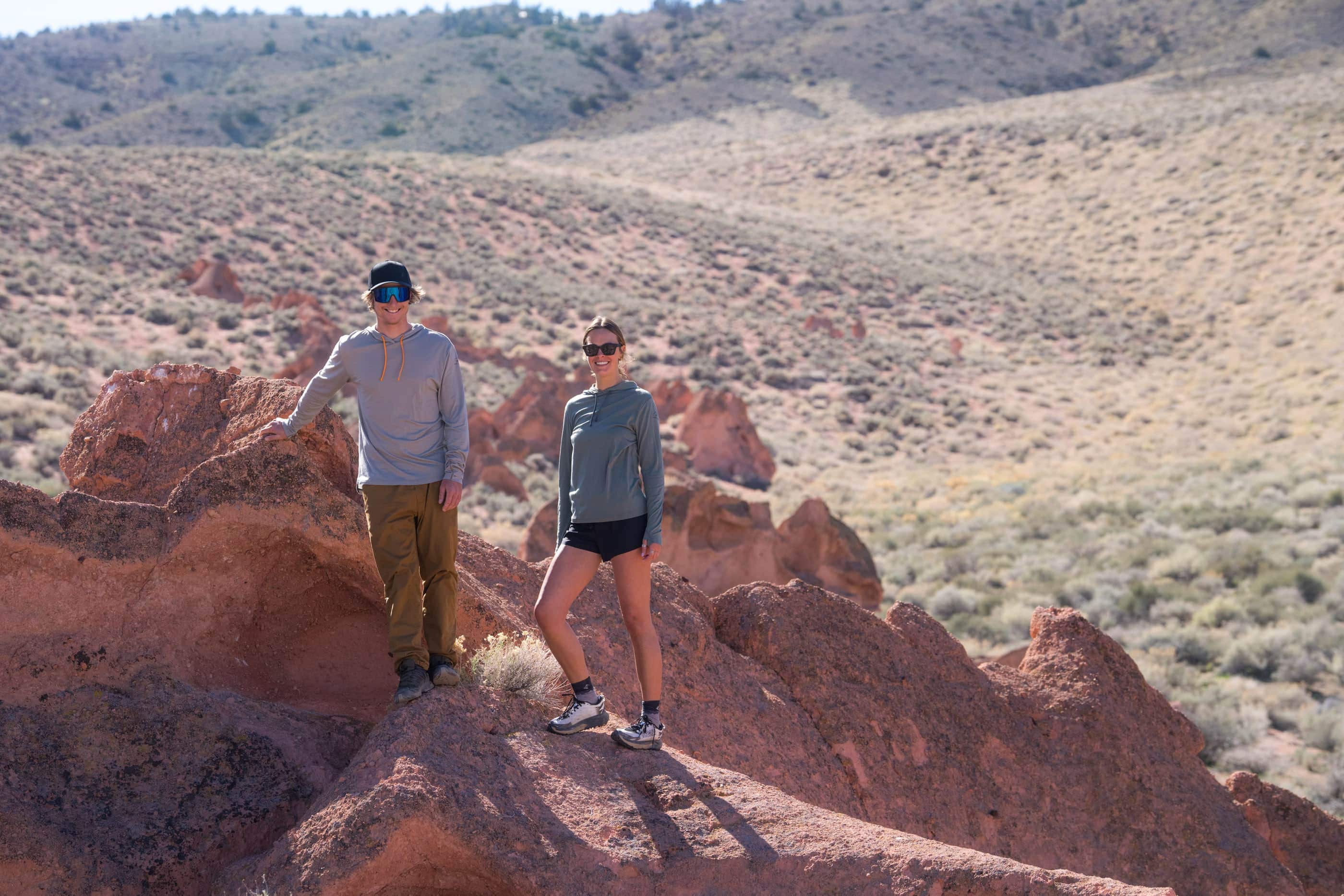 two hikers wearing sunglasses and Ridge Merino Wool Sun Hoodies on a rocky hike