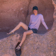 a woman sitting on a rock wearing a pink Merino and Tencel long sleeve shirt