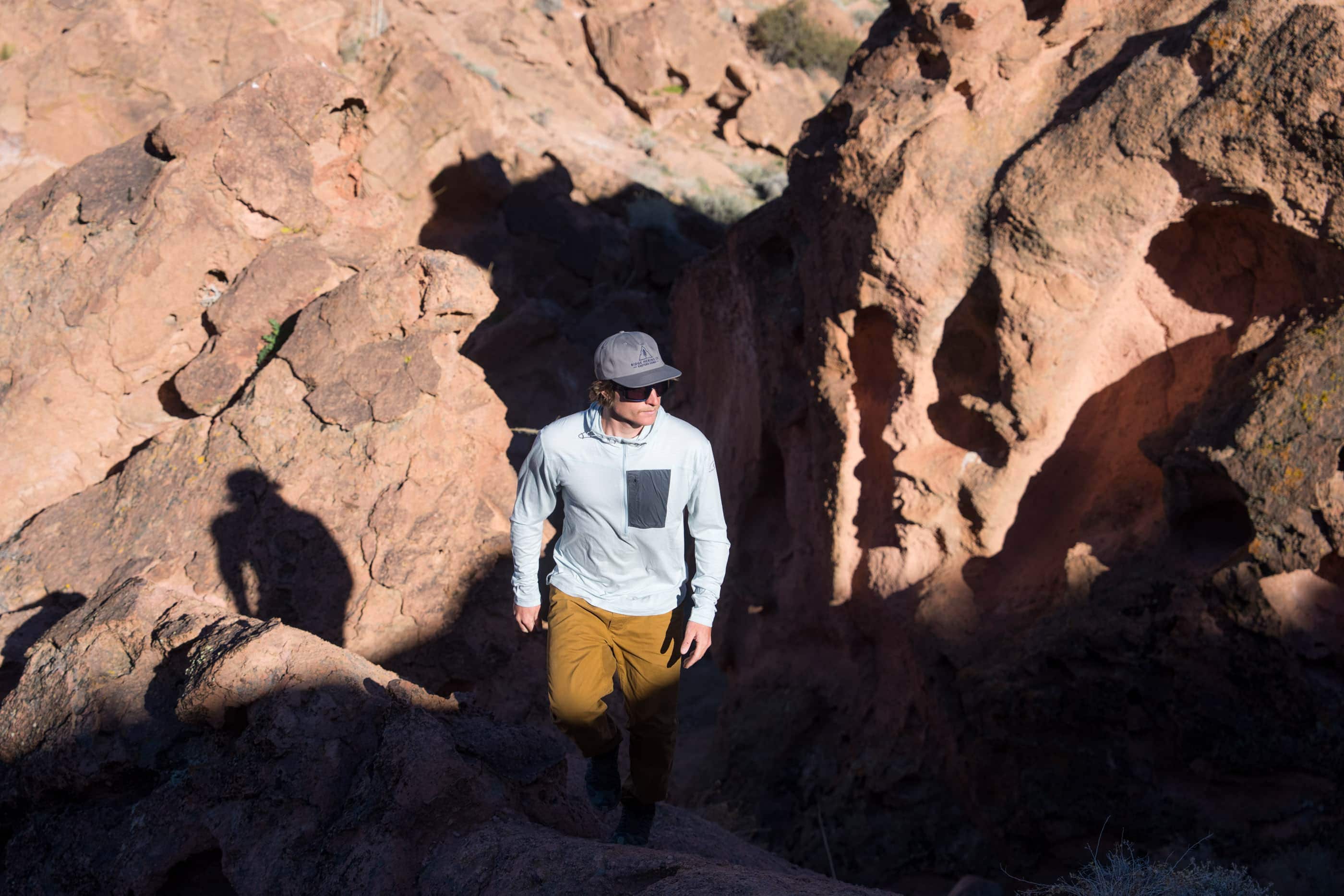 a man hiking in a sunny, rocky area in a Solstice Pro Sun Hoodie