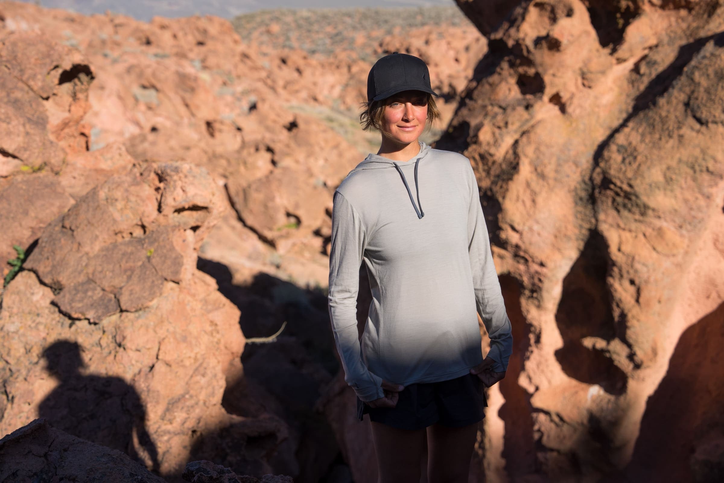 a woman wearing a Rock Ridge Solstice Sun Hoodie in a rocky desert landscape