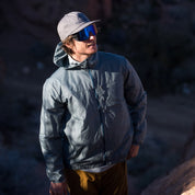 a man wearing a blue Merino windbreaker on a hike