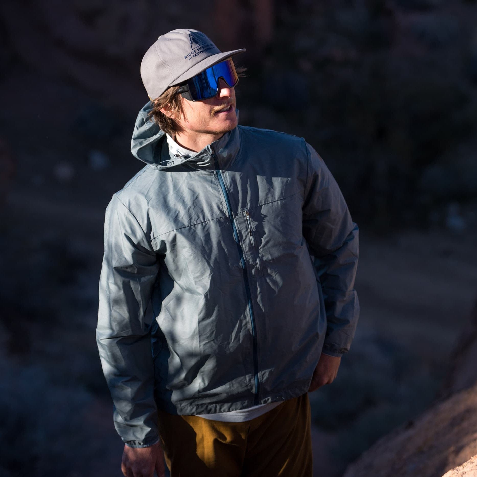 a man wearing a blue Merino windbreaker on a hike