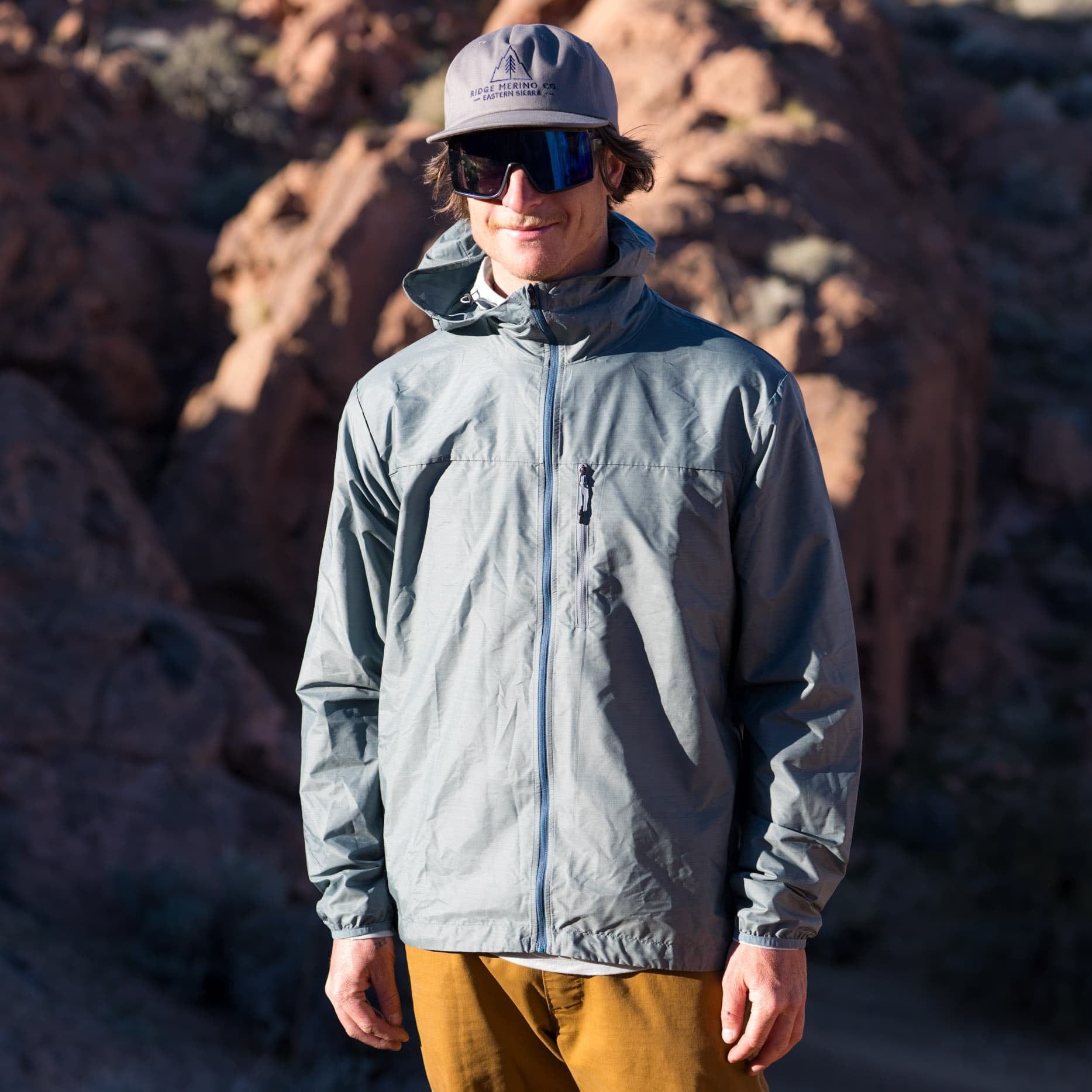 a man wearing a blue Merino windbreaker on a hike