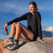 a hiker sitting on a rock wearing shorts and a black Merino Tencel Canopy Shirt