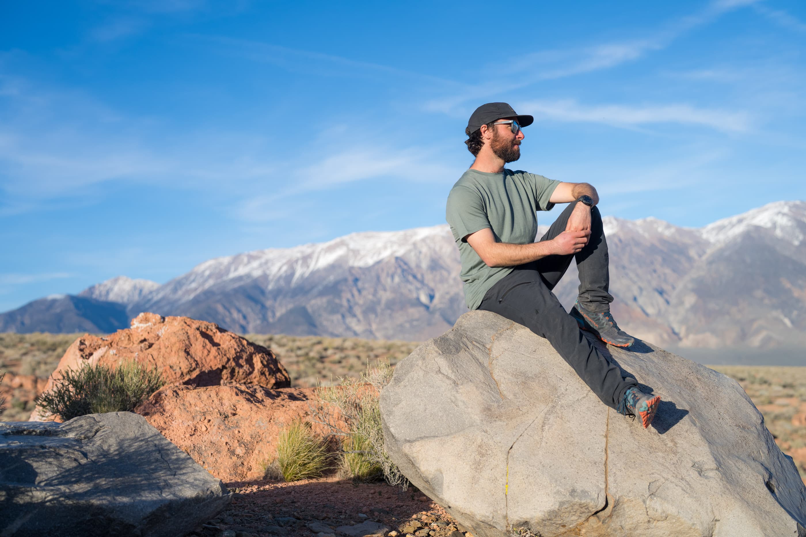 a man smiles sitting on a rock wearing a Ridge Merino T-shirt