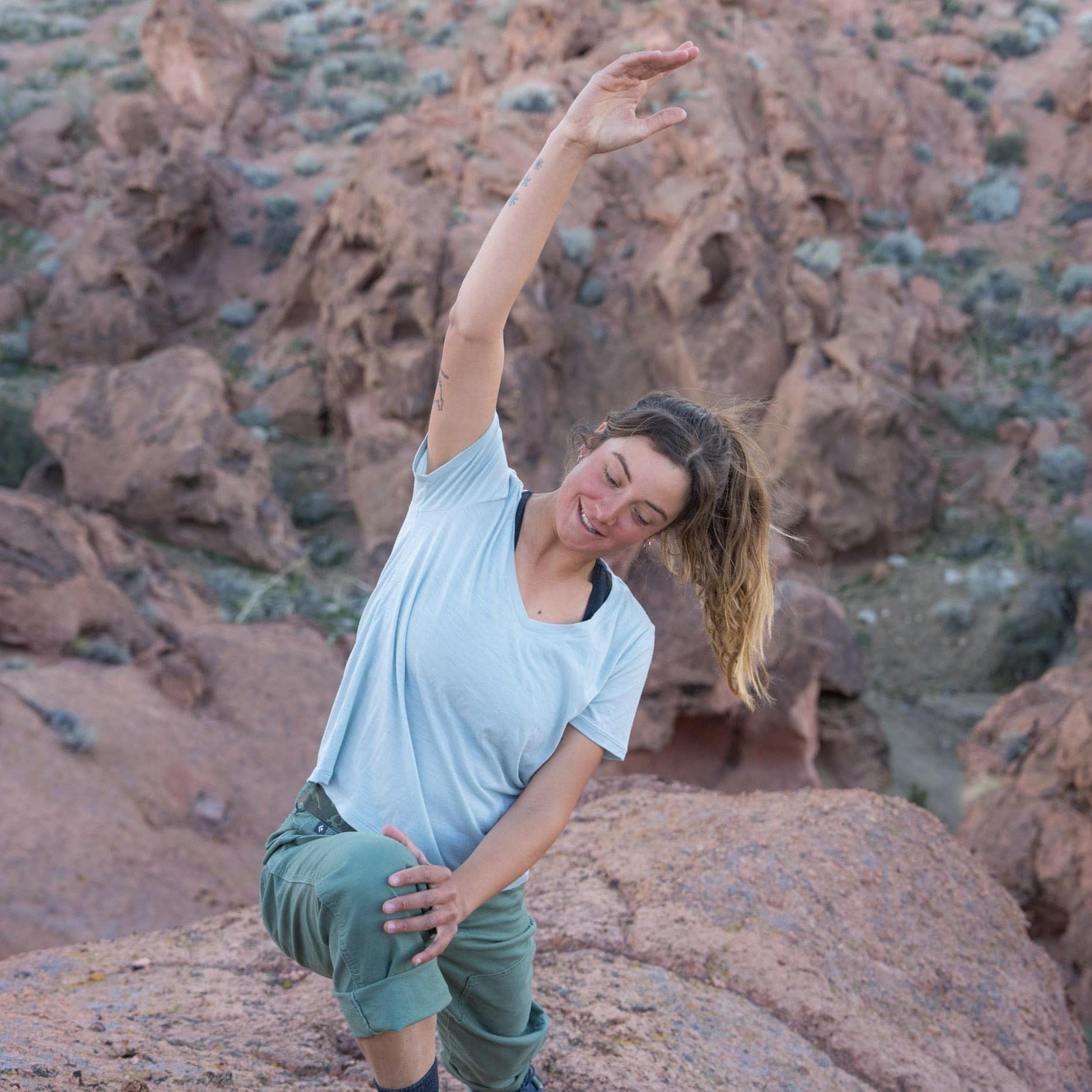 a woman stretching wearing a v-neck Merino t-shirt