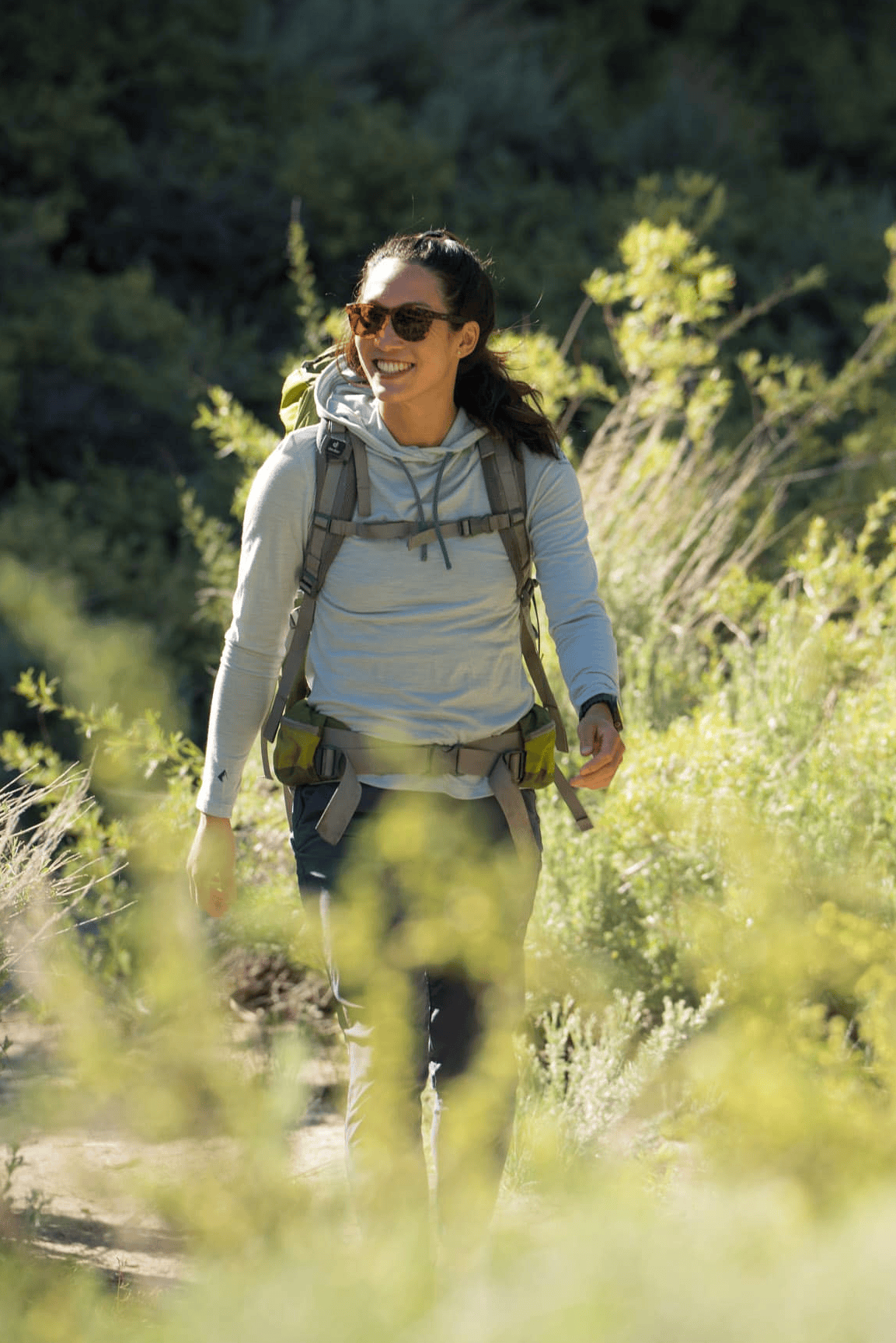 a woman smiles hiking in a Solstice Sun Hoodie