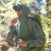 a man zipping up his Windshifter Merino Windbreaker on a backpacking trip