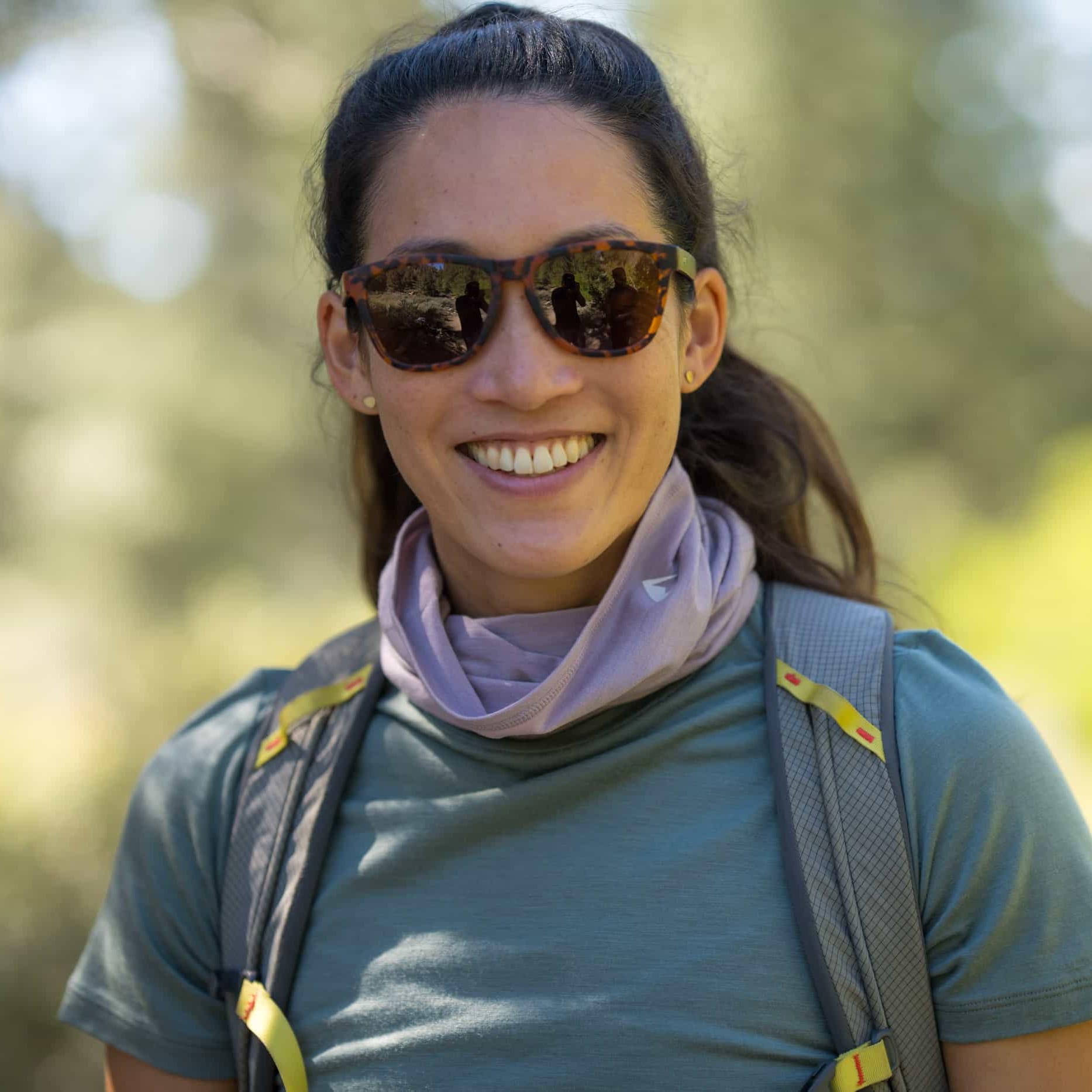 a woman smiles on a hike wearing a Sierra Merino Wool Neck Tube in Dusty Lilac