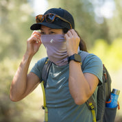 a woman adjusting her Sierra Merino Wool Neck Tube on a hike