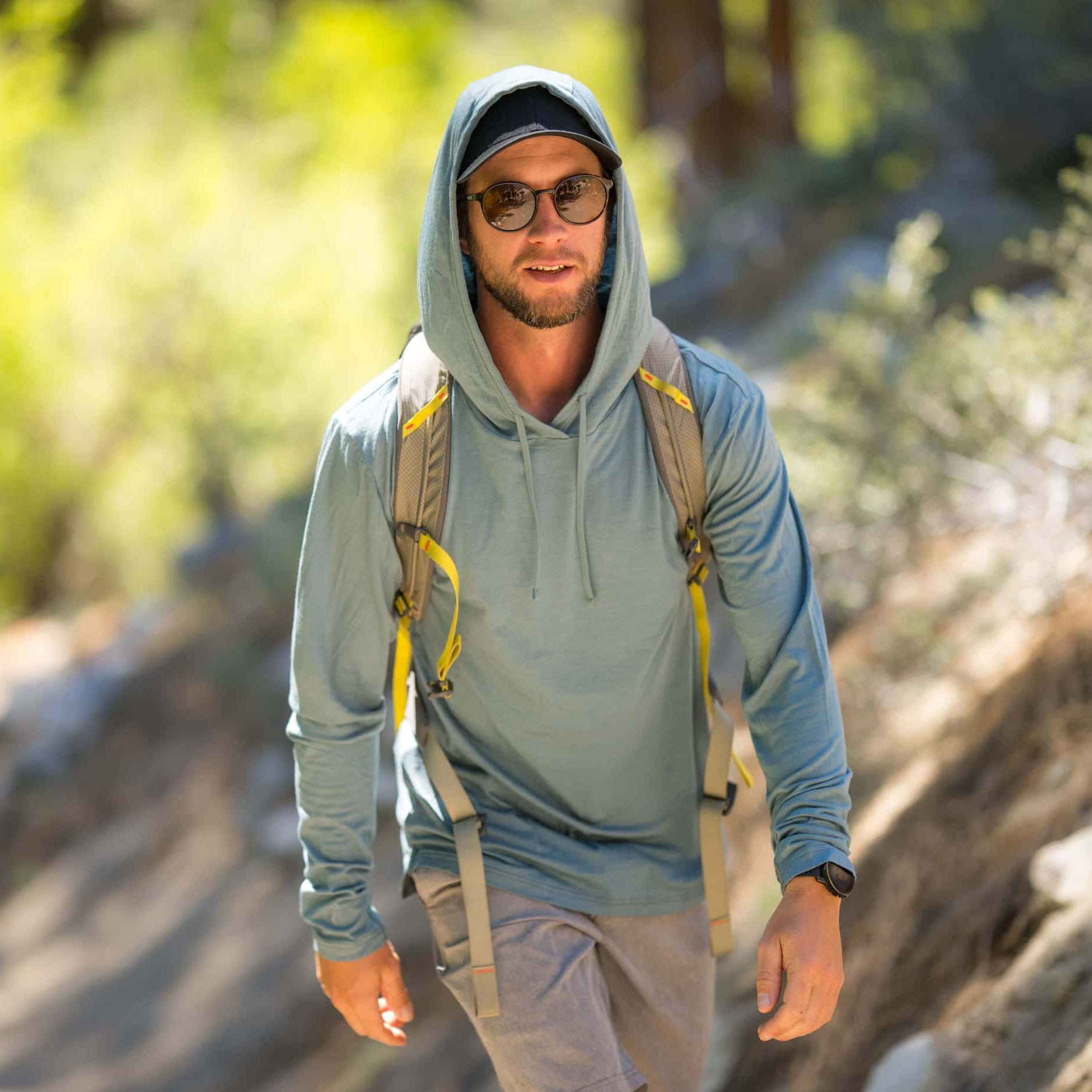 a man hiking in a Solstice Merino Sun Hoodie with the hood up