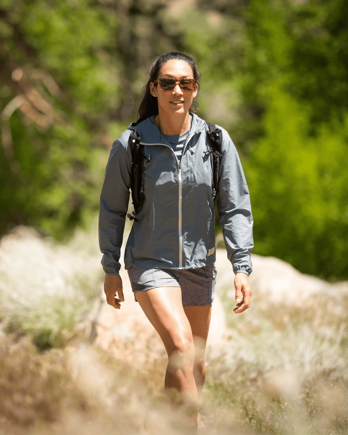 a woman hiking in a blue Windshifter Windbreaker