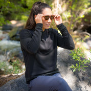 a woman sitting on a rock wearing a black Cloudripper Pullover