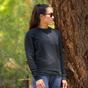 a woman stands next to a tree wearing a black Cloudripper Pullover