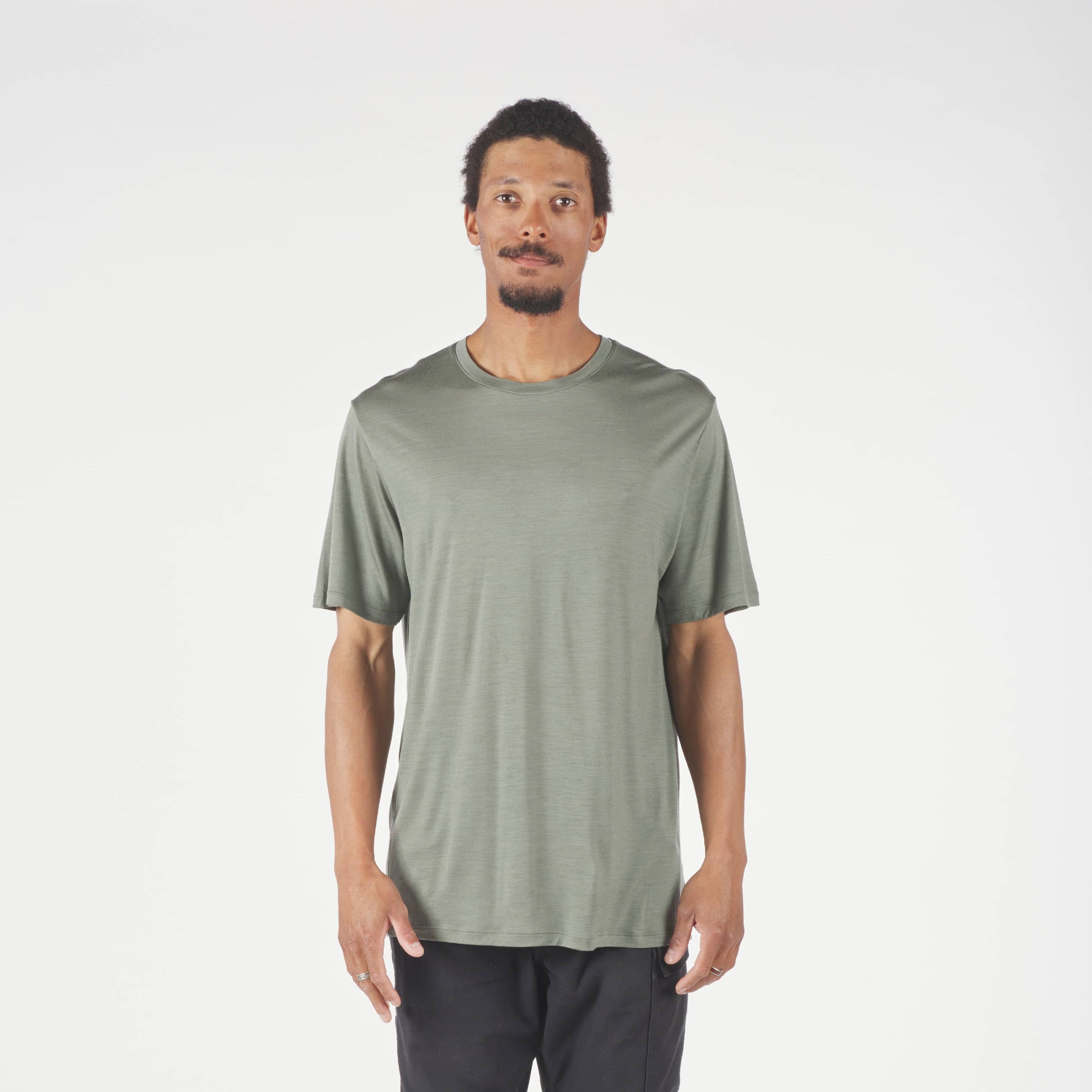 Man wearing a green t-shirt and dark pants on a white background