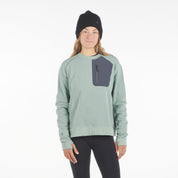 a woman wearing a Cloudripper Crew Neck Pullover in Iceberg Green with black Aspect base layer bottoms and a black Layton beanie