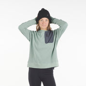 a woman wearing a Cloudripper Crew Neck Pullover in Iceberg Green with black Aspect base layer bottoms and a black Layton beanie