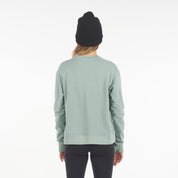 a woman wearing a Cloudripper Crew Neck Pullover in Iceberg Green with black Aspect base layer bottoms and a black Layton beanie
