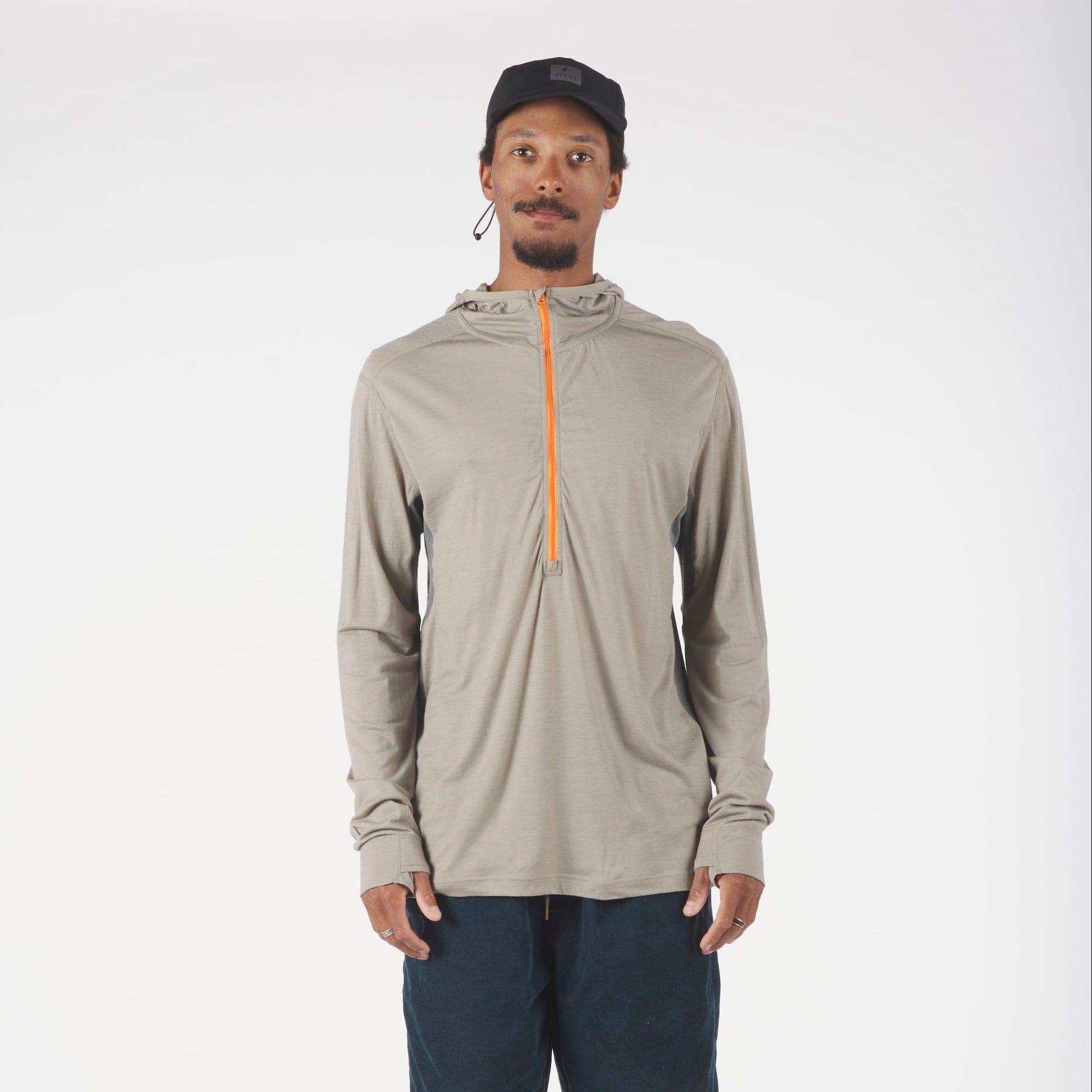 Man wearing a beige long-sleeve hoodie with an orange zipper and navy shorts on a white background