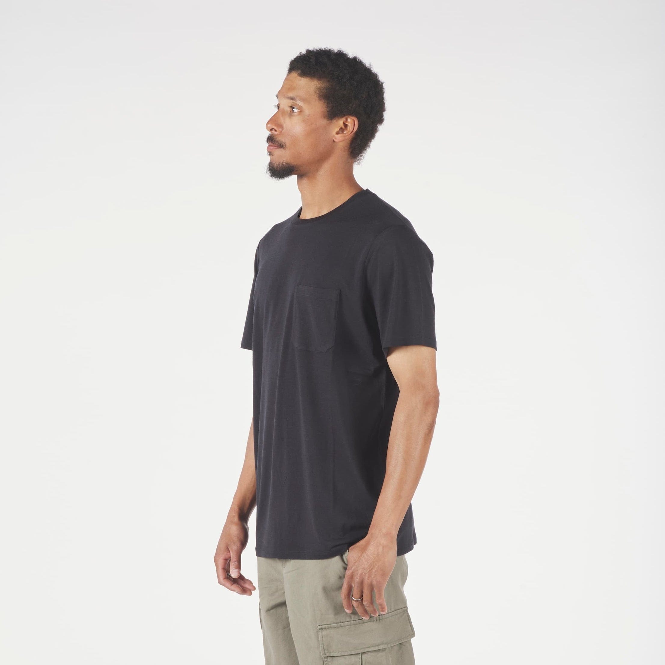 Man wearing a black t-shirt and green cargo pants on a white background