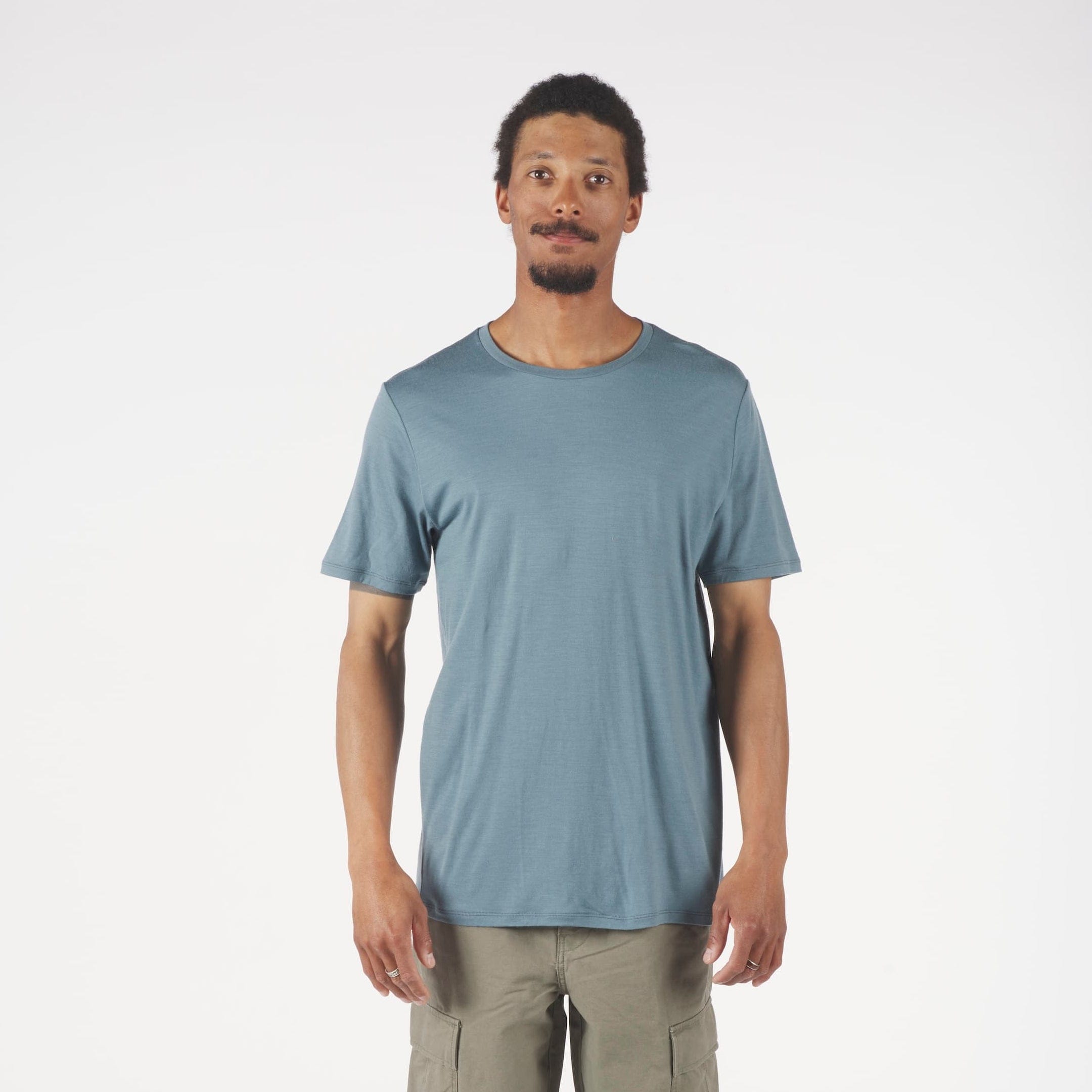Man wearing a blue t-shirt and beige pants on a white background