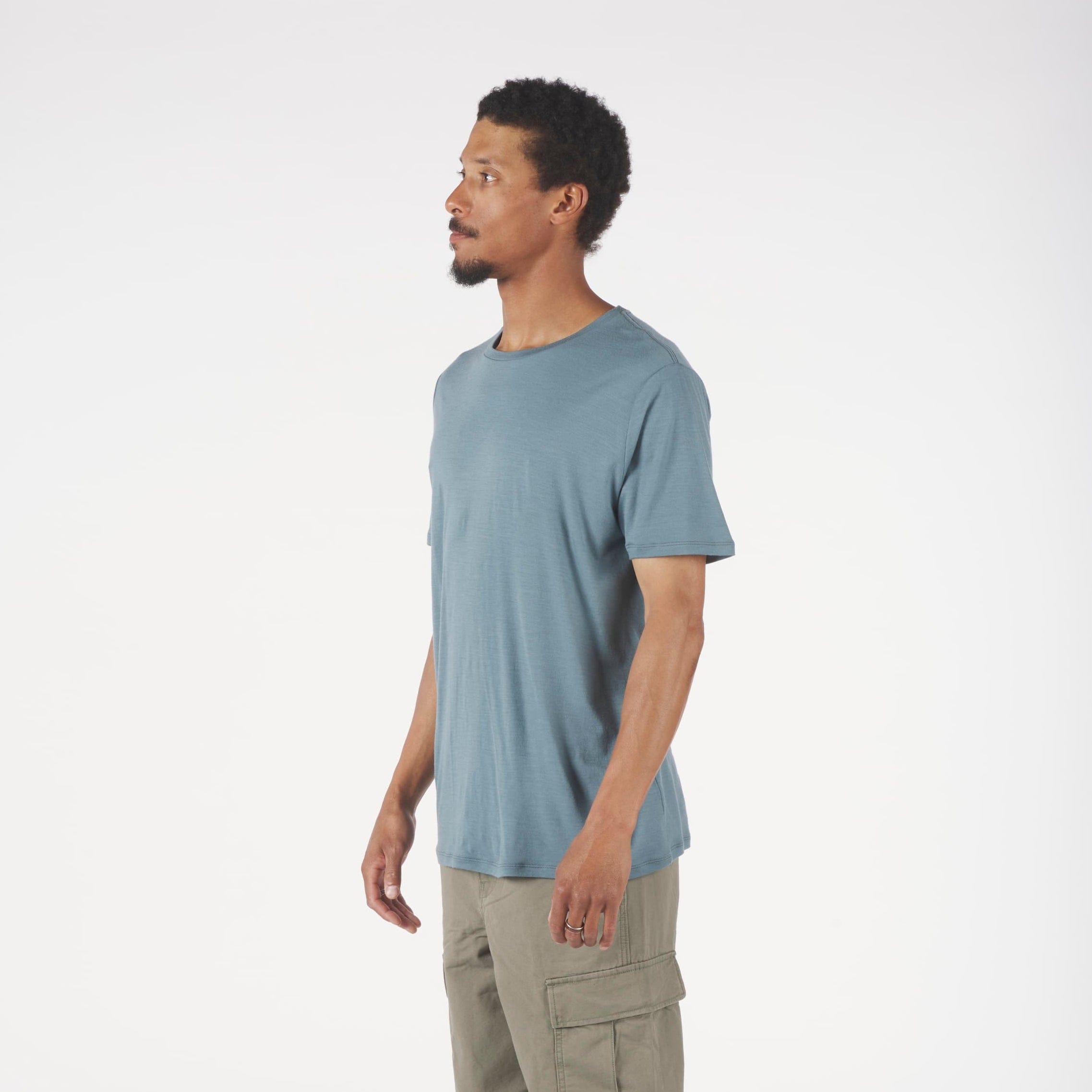 Man wearing a light blue t-shirt and beige cargo pants on a white background