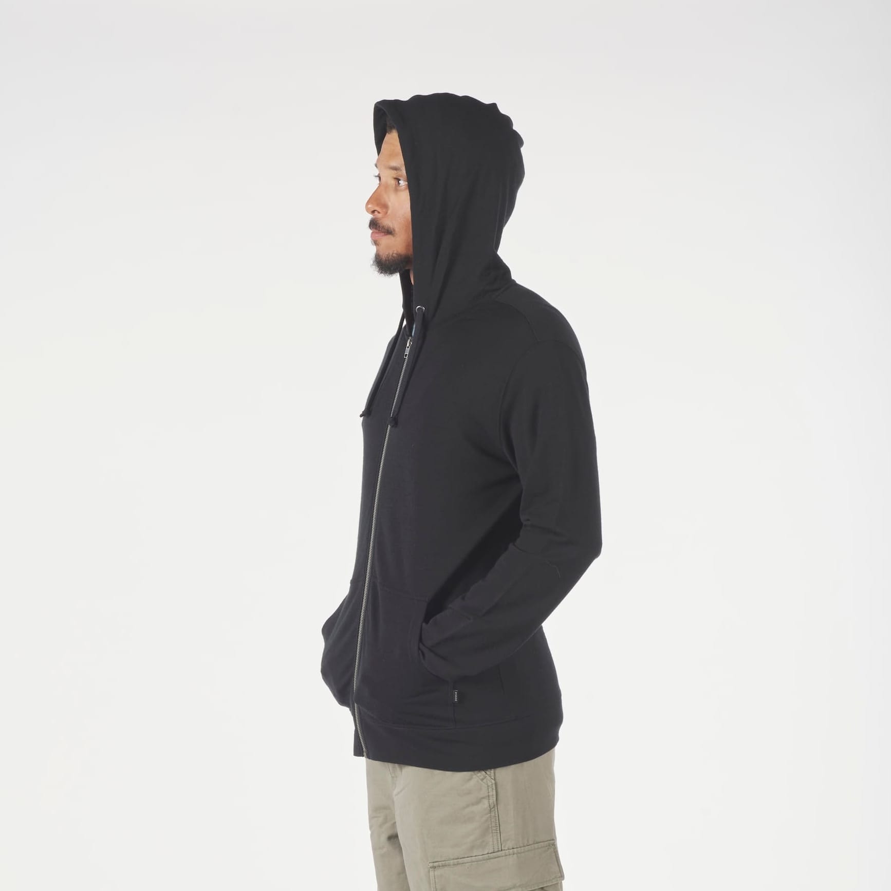 a man wearing a Ridge Merino Traveler Hoodie in black with the hood up