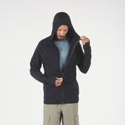 Person wearing a black hoodie and beige pants on a white background