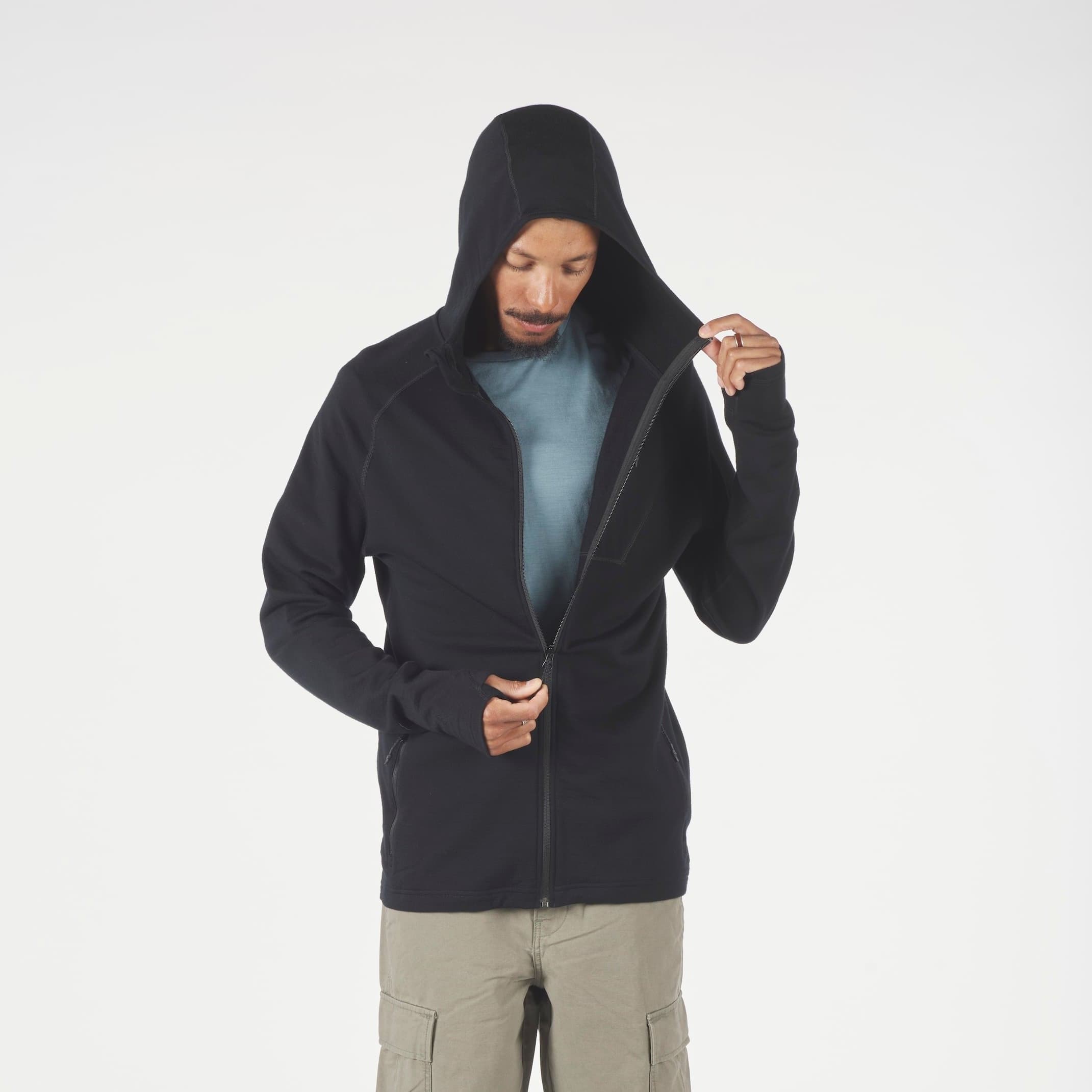 Person wearing a black hoodie and beige pants on a white background