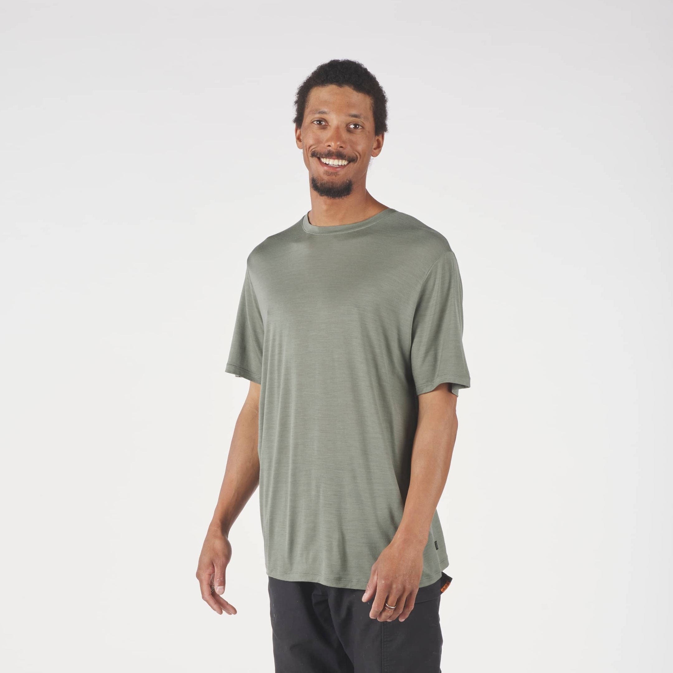 Man wearing a green t-shirt and dark pants on a white background