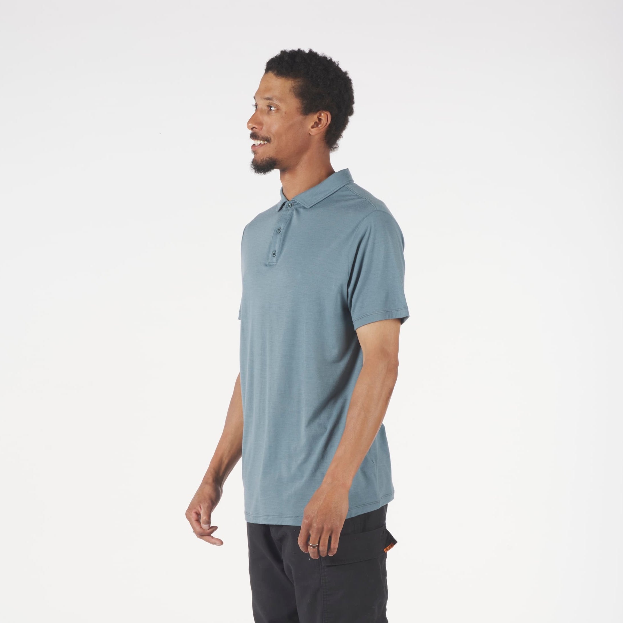 Man wearing a light blue polo shirt and dark pants on a white background