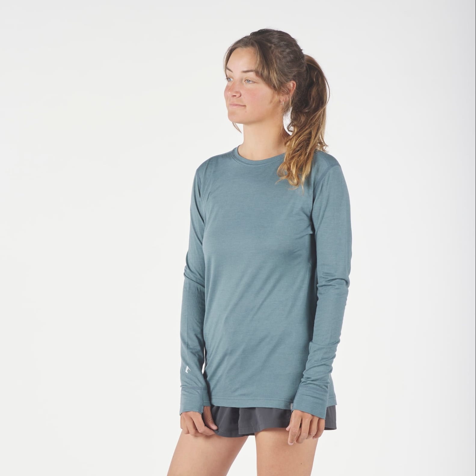a woman wearing a Pursuit Ultralight Merino Long Sleeve Shirt and running shorts