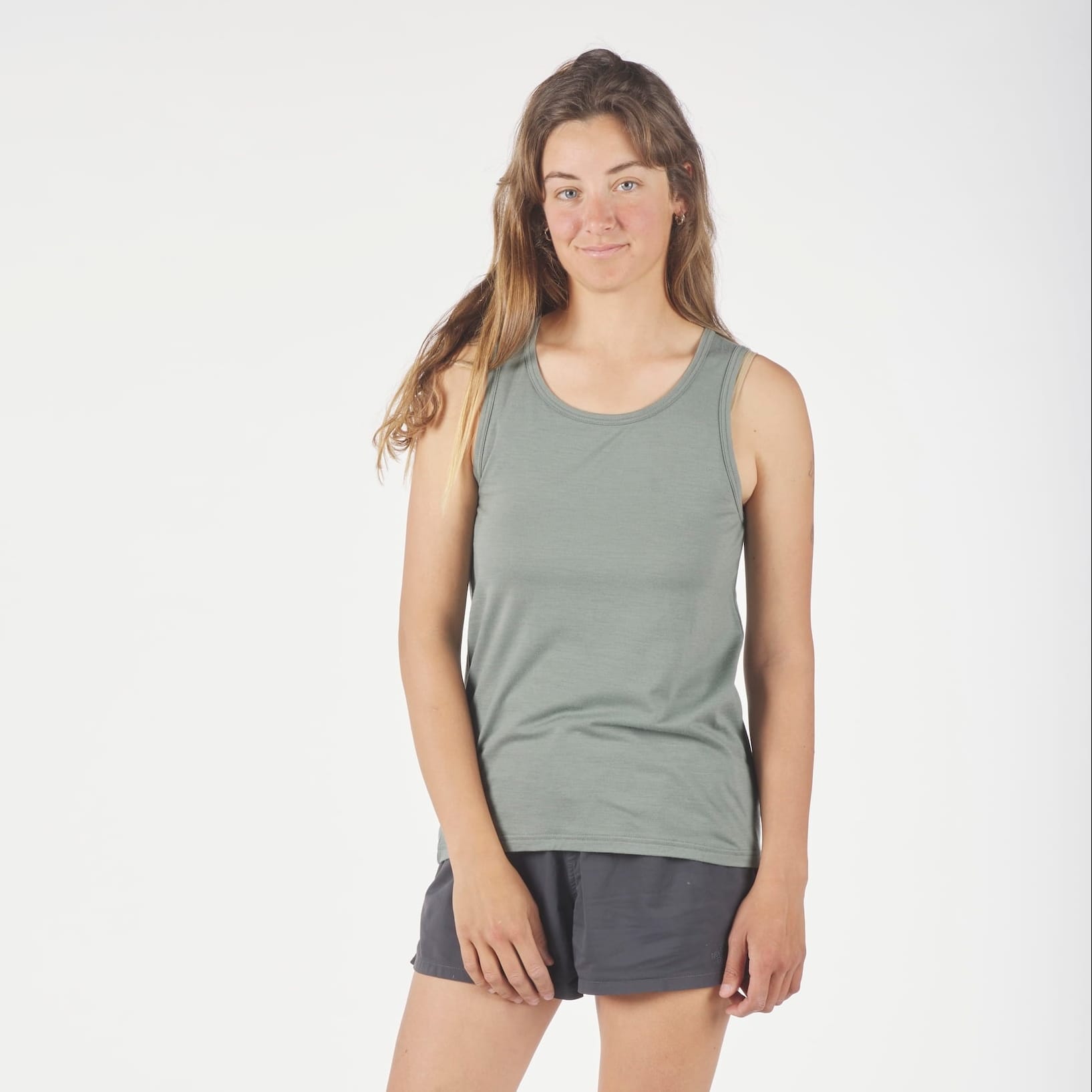 a woman wearing a green Journey Merino Wool Tank Top