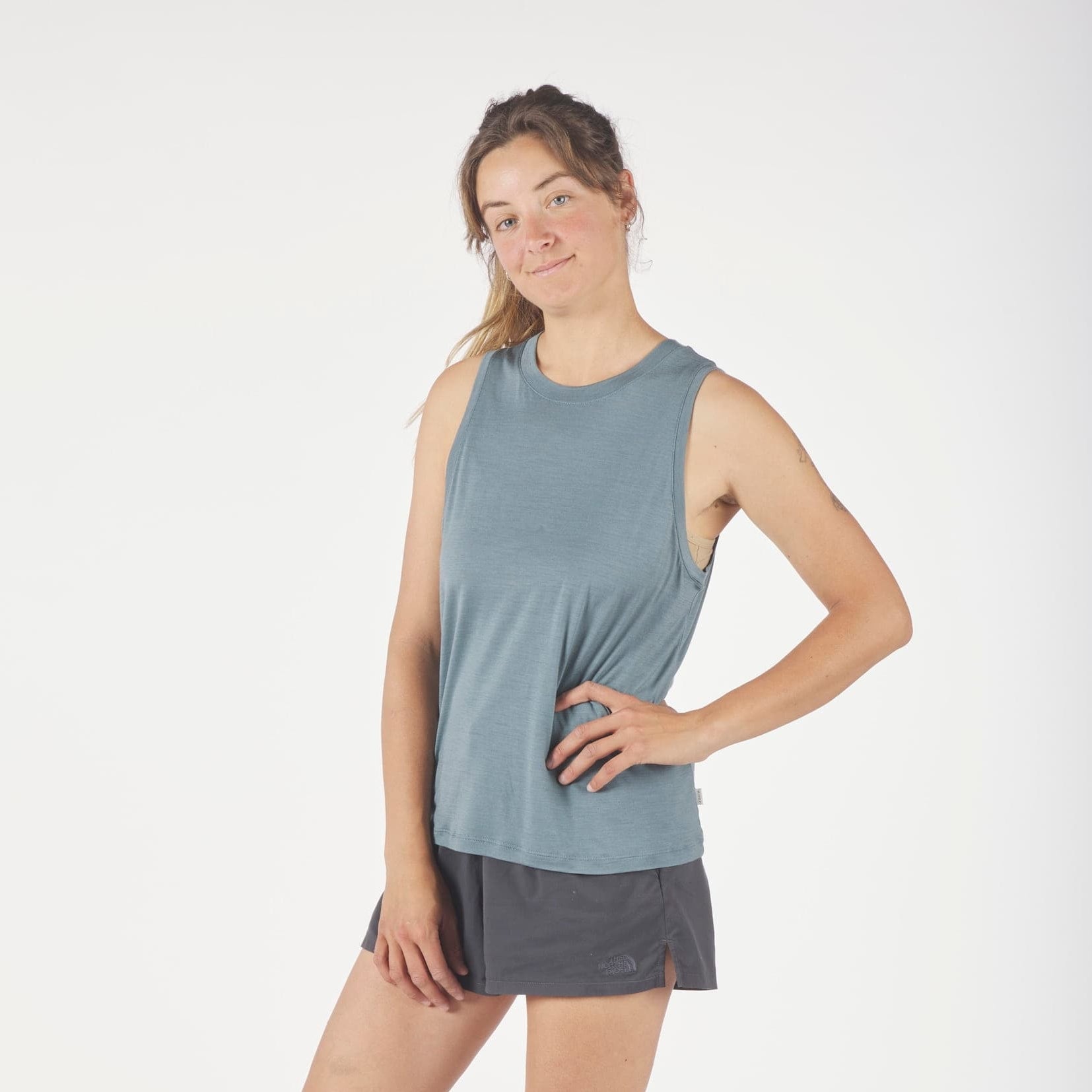 a woman wearing a blue Canopy Merino Tencel Tank Top with running shorts