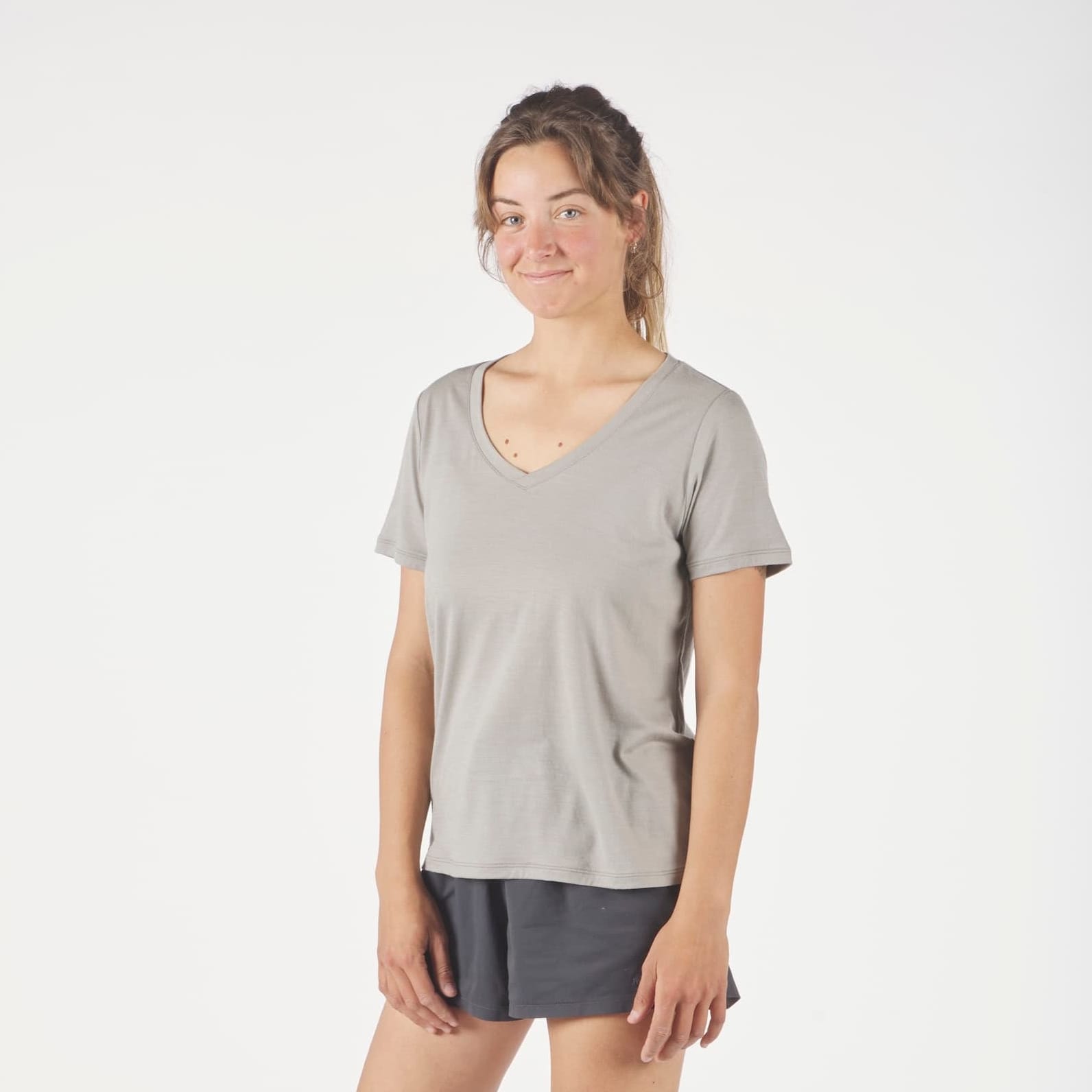 a woman wearing a Journey Merino Wool V-Neck T-Shirt in Rock Ridge with running shorts