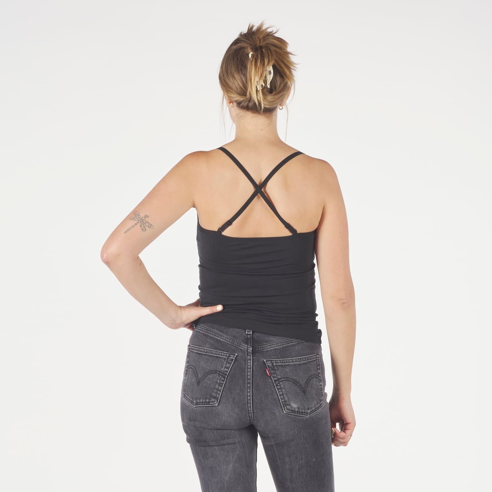 a woman wearing a Ridge Merino Wool Cami Tank Top in black with the back straps crossed