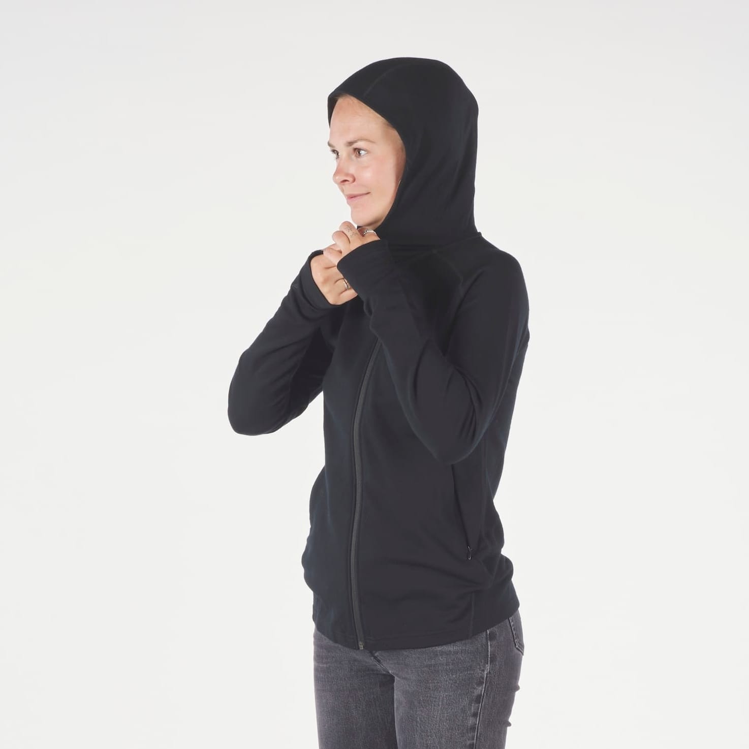 a woman zips up her black Hyde Hoodie