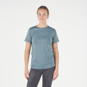 a woman wearing a blue Pursuit T-Shirt with black jeans